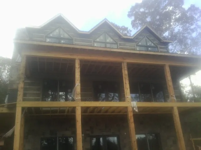 Dormers and porch framing on a large log home under construction — Roof Coating work by our crew in Park Hall
