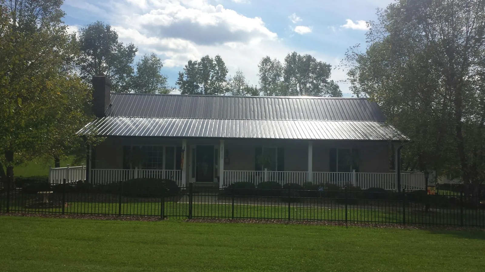 Gray metal roof on a brick ranch with a full width front porch — Gutter Guard Installation work by our crew in Park Hall