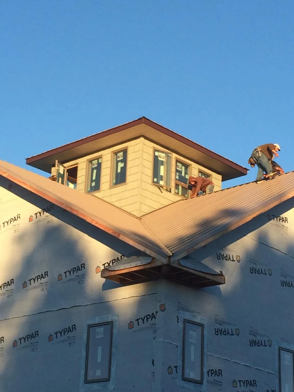 Roofers working around a rooftop cupola on a new metal roof at sunset — Roof Waterproofing in Park Hall by Roofing Brothers